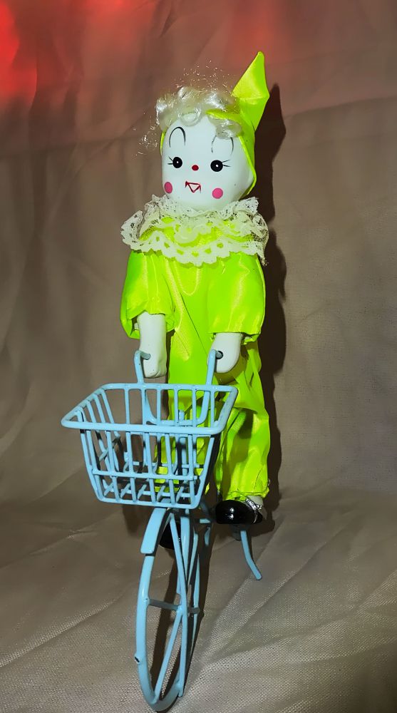 Pierrot in grünem Kostüm auf Fahrrad
